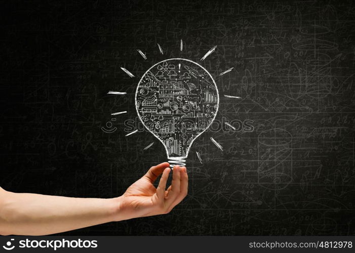 Light in darkness. Human hand on dark background holding light bulb