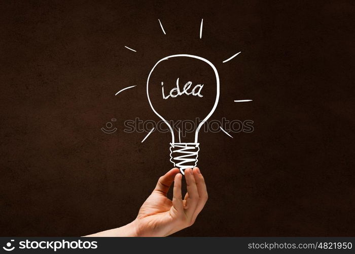 Light in darkness. Human hand on dark background holding light bulb