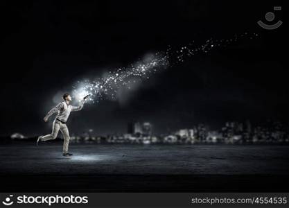Light of education in darkness. Funny student guy running in darkness with opened book in hand