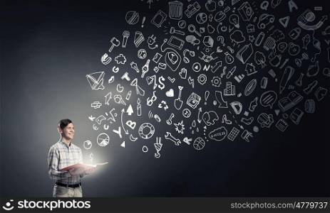 Light of education in darkness. Young man with book in hands and light out of pages