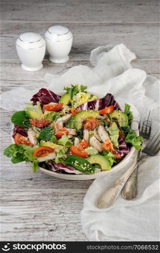 Light salad organic mix lettuce with tomatoes, avocado, slices of chicken breast, seasoned roasted sesame seeds.