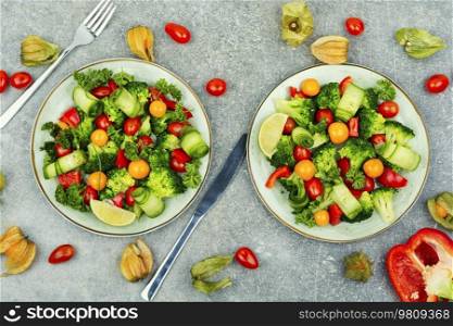 Light salad with broccoli, tomato, cucumber, bell pepper and physalis. Top view. Healthy summer salad with physalis.