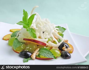 light salad with chicken, grapes, nectarines, sesame, with lemon dressing, decorated with fried rice noodles with mint