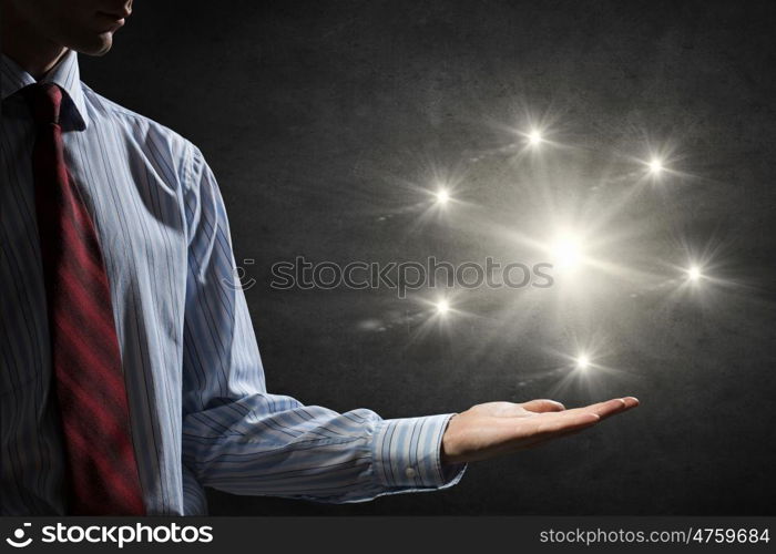 Light spot in darkness. Businessman holding light flash in palm on dark background