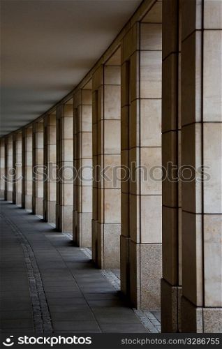 Light streams through a curved line of square faced pillars