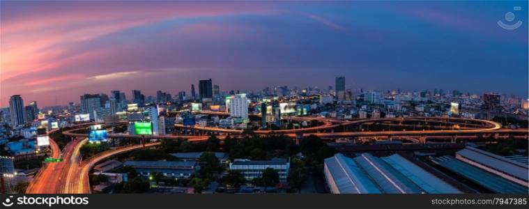 Light tail of Transportation car on road way at night life and Business Building Bangkok city area background as panorama, high angle birds eye view