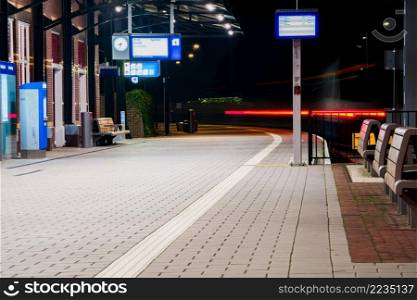 Light trail of the local train in the railway station at the night. Public transportation in a city. Tram leaving the station.
