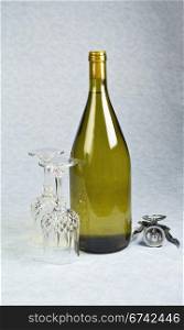 Light white wine in unopened bottle with two wine glasses and cork screw on blue table cloth