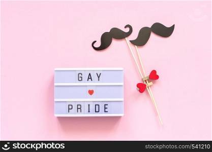 Lightbox text Gay pride and couple paper mustache props on pink background. Concept Homosexuality gay love National Day Against Homophobia or International Gay Day Top view Greeting card.. Lightbox text Gay pride and couple paper mustache props on pink background. Concept Homosexuality gay love National Day Against Homophobia or International Gay Day Top view Greeting card