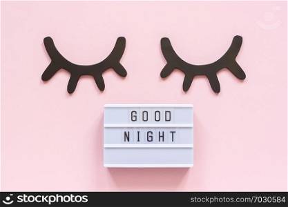 Lightbox text Good Night and decorative wooden black eyelashes, closed eyes on pink paper background. Concept Sweet dreams Greeting card Top view Creative flat lay.. Lightbox text Good Night and decorative wooden black eyelashes, closed eyes on pink paper background. Concept Sweet dreams Greeting card Top view Creative flat lay