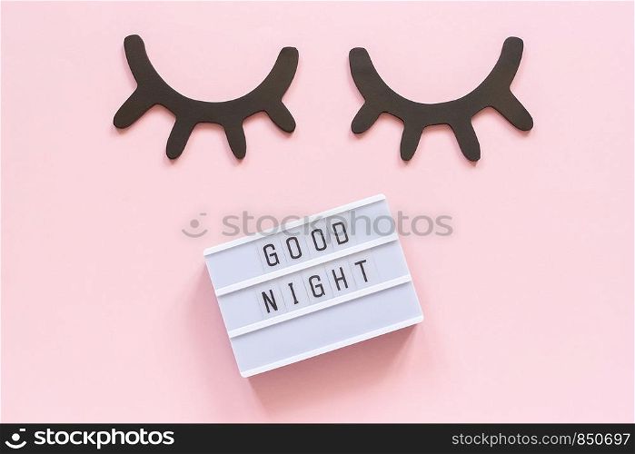 Lightbox text Good Night and decorative wooden black eyelashes, closed eyes on pink paper background. Concept Sweet dreams Greeting card Top view Creative flat lay.. Lightbox text Good Night and decorative wooden black eyelashes, closed eyes on pink paper background. Concept Sweet dreams Greeting card Top view Creative flat lay