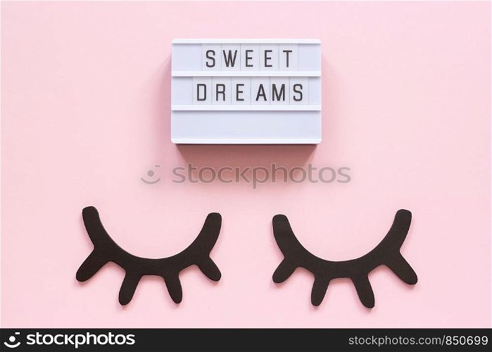 Lightbox text Sweet dreams and decorative wooden black eyelashes, closed eyes on pink paper background. Concept Good night Greeting card Top view Creative flat lay.. Lightbox text Sweet dreams and decorative wooden black eyelashes, closed eyes on pink paper background. Concept Good night Greeting card Top view Creative flat lay