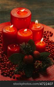 Lighted candles with red colored pearls around on a wooden table