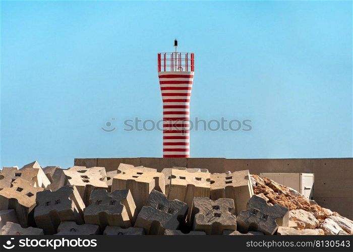 Lighthouse in red and white color in front of a sunny blue sky.