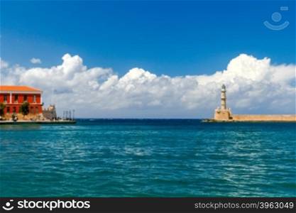 Lighthouse in the old harbor of Chania, on a background of blue sea and clouds.