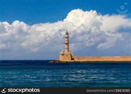 Lighthouse in the old harbor of Chania, on a background of blue sea and clouds.