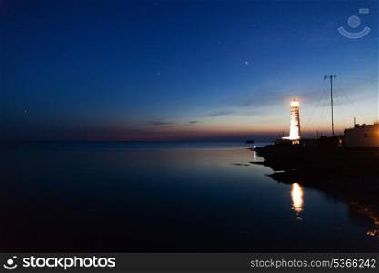 Lighthouse on the water edge near sea at night&#xA;