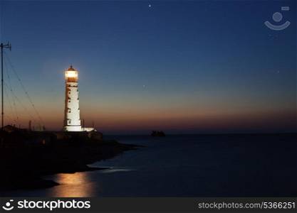 Lighthouse on the water edge near sea at night&#xA;
