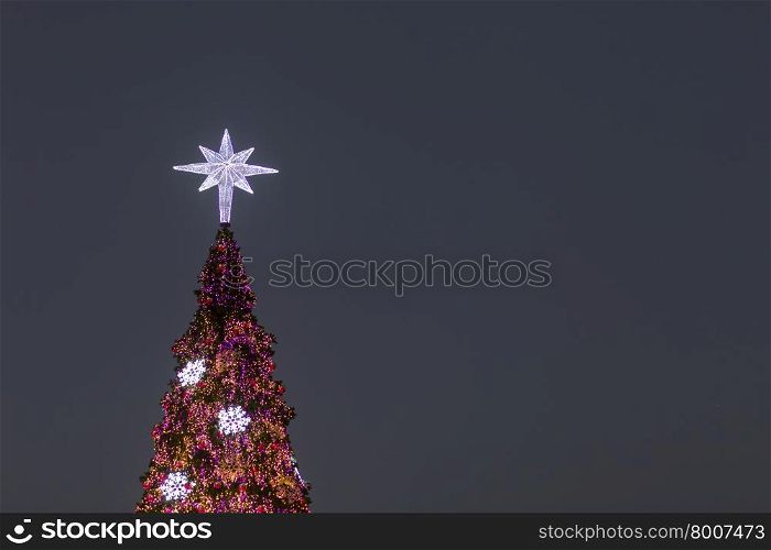 Lighting of the Christmas tree. At the peak of the Christmas tree decorated with lights during the night.