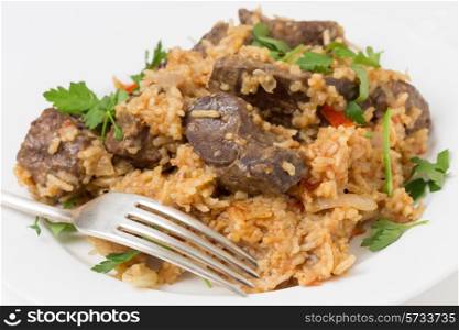lightly fried lambs liver chunks baked on top of a pilaf of rice, onion, tomato, capsicum and dried currants in a chicken broth, on a small plate garnished with flat-leaf italian parsley. This is an outstanding recipe.