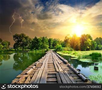 Lightning over a wooden bridge on a river
