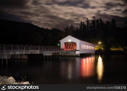 Lights glow and reflect in the water night scene Lowell Covered Bridge