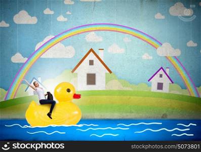 Like a child again. Young happy businesswoman riding yellow rubber duck