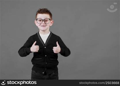 Like. Portrait of happy little schoolboy with glasses smiling at camera and doing thumbs up gesture, showing agree cool approval sign. indoor studio shot isolated on gray background.. Like. Portrait of happy little schoolboy with glasses smiling at camera and doing thumbs up gesture, showing agree cool approval sign. indoor studio shot isolated on gray background