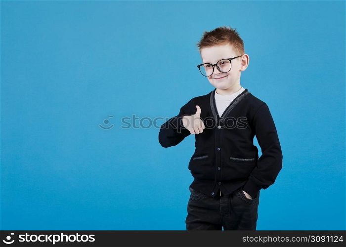 Like. Portrait of happy little schoolboy with glasses smiling at camera and doing thumbs up gesture, showing agree cool approval sign. indoor studio shot isolated on blue background.. Like. Portrait of happy little schoolboy with glasses smiling at camera and doing thumbs up gesture, showing agree cool approval sign. indoor studio shot isolated on blue background