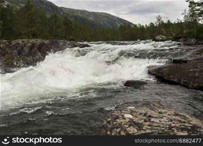 likholefossen waterfall in norway with mountains as background