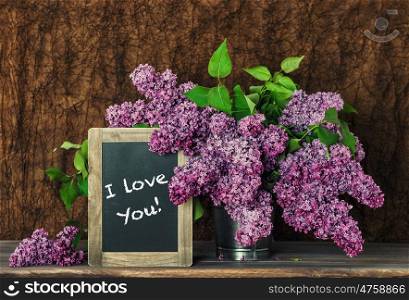 Lilac flowers and blackboard with sample text I love You!