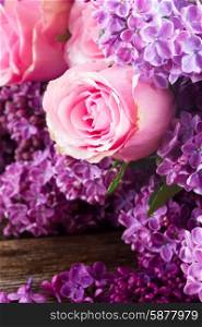 Lilac flowers. Purple Lilac fresh flowers with pink roses on wooden table close up