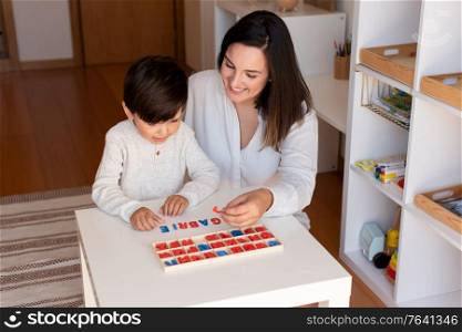 Lillte Kid learning to write and read with a alphabet and mother or teacher help. Homeshooling. Learning Community. Montessori School
