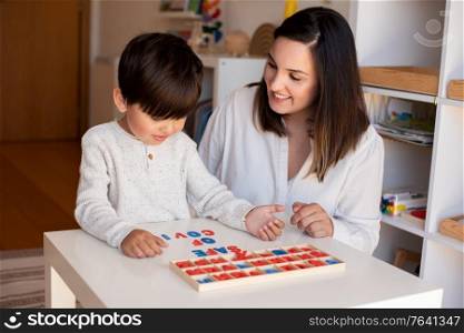 Lillte Kid learning to write and read with a alphabet and mother or teacher help. Homeshooling. Learning Community. Montessori School