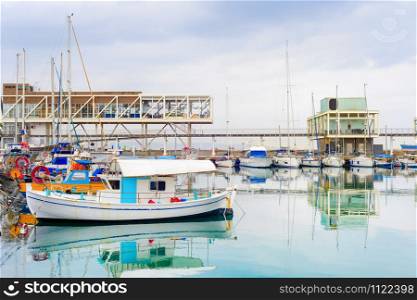 Limassol city harbor view, moored fishing motor boats, restaurants on the pier under heavy sky with rainy clouds, Cyprus