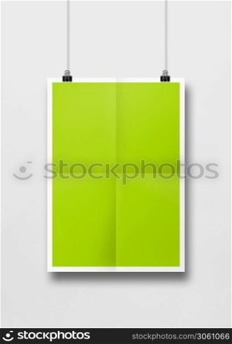 Lime green folded poster hanging on a white wall with clips. Blank mockup template. Lime green folded poster hanging on a white wall with clips