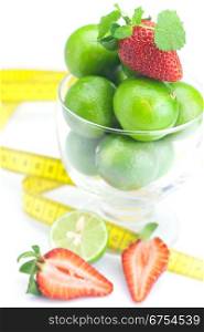 lime in a glass cup, measuring tape, strawberry and mint isolated on white