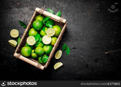 Lime with leaves in a basket. On a black background. High quality photo. Lime with leaves in a basket.