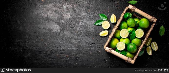 Lime with leaves in a basket. On a black background. High quality photo. Lime with leaves in a basket.