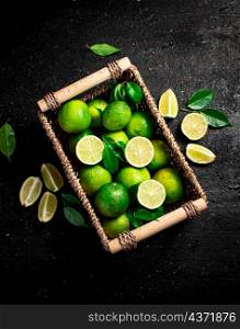 Lime with leaves in a basket. On a black background. High quality photo. Lime with leaves in a basket.