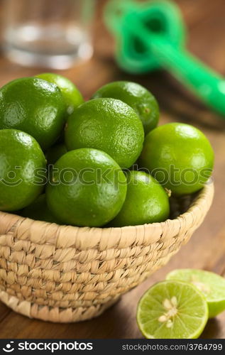 Limes in woven basket with lime squeezer and glass in the back (Selective Focus, Focus on the two upper limes)