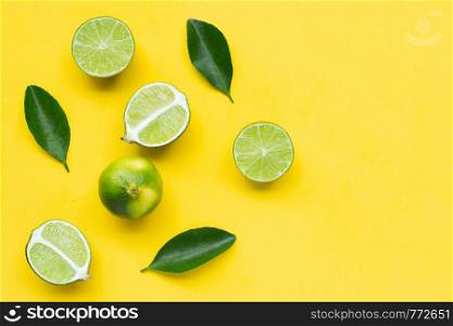 Limes with leaves on yellow background. Copy space