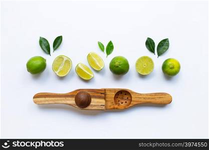 Limes with wooden lime squeezer on white background