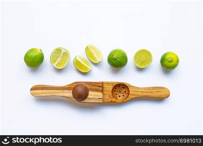 Limes with wooden lime squeezer on white background.