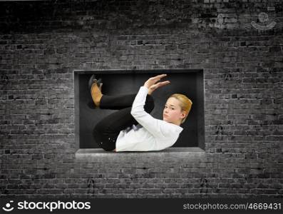 Limited and restricted. Young woman trapped in stone cube in wall