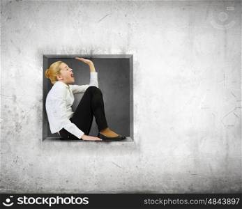 Limited and restricted. Young woman trapped in stone cube in wall