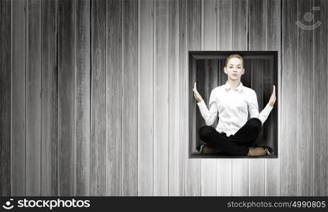 Limited and restricted. Young woman trapped in wooden cube in wall