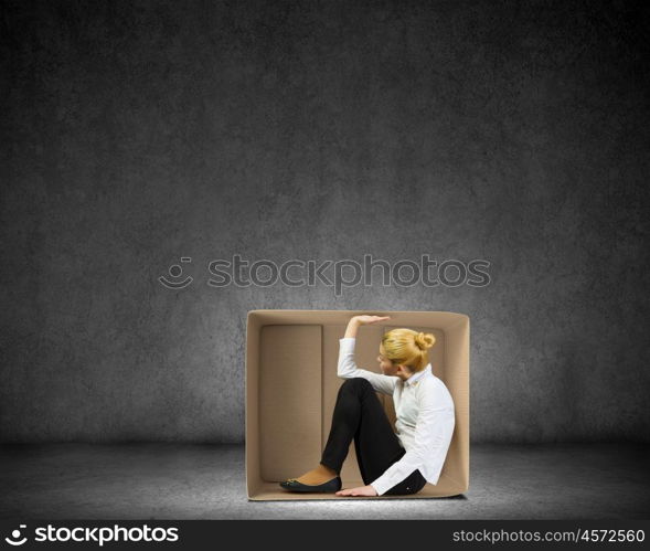 Limited possibilities. Young businesswoman sitting in carton box and feeling uncomfortable