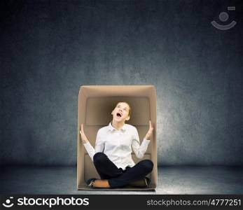 Limited possibilities. Young businesswoman sitting in carton box and feeling uncomfortable