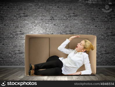 Limited possibilities. Young businesswoman sitting in carton box and feeling uncomfortable